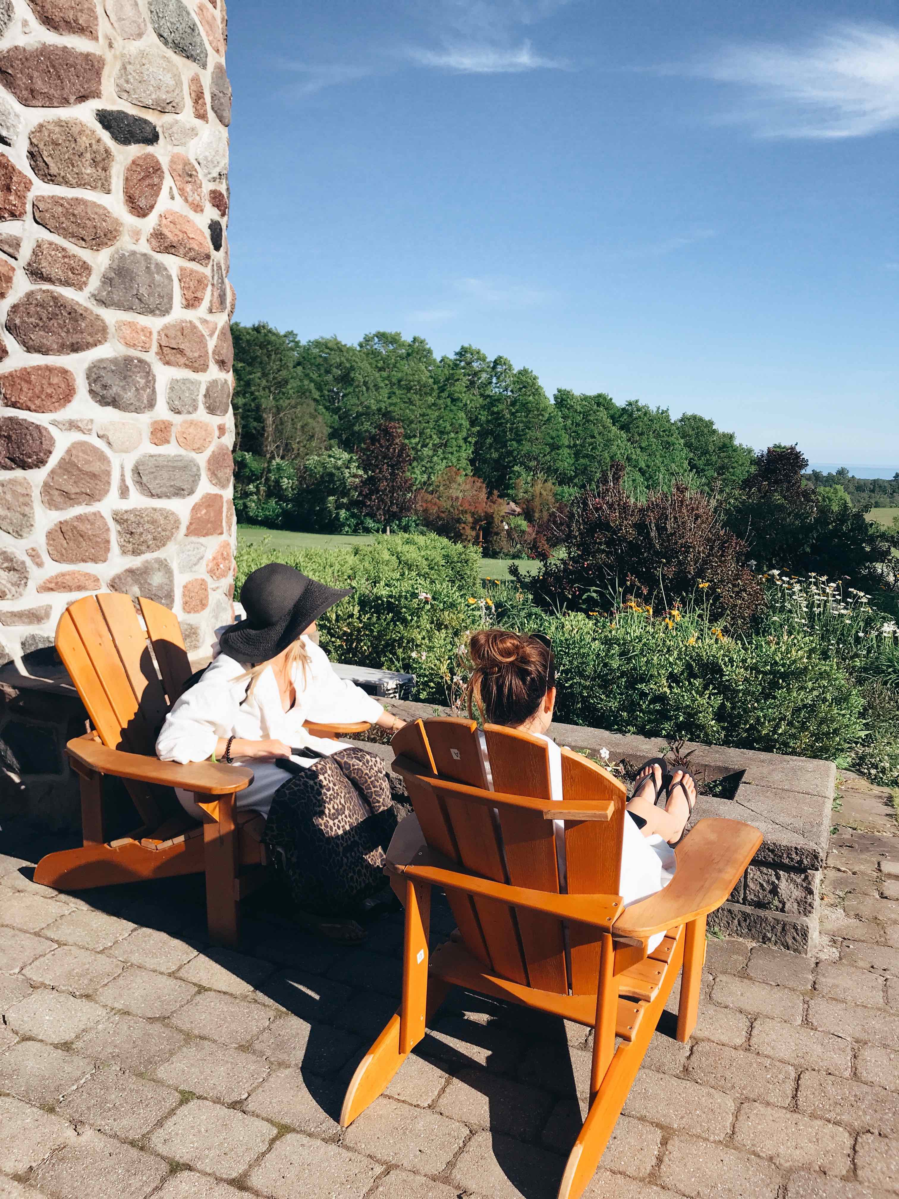 two women at ste annes spa sitting on orange lawn chairs looking at the trees and scenery